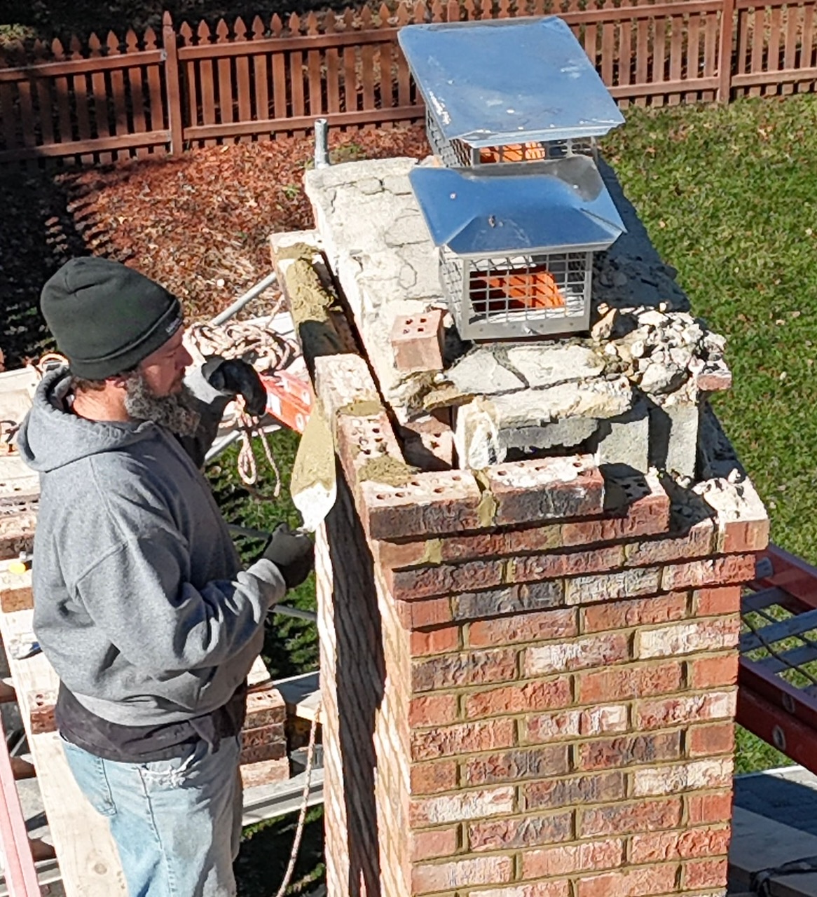 Three Hills Masonry mason working at the top of a brick chimney during a chimney repair on a Greater Boston home.