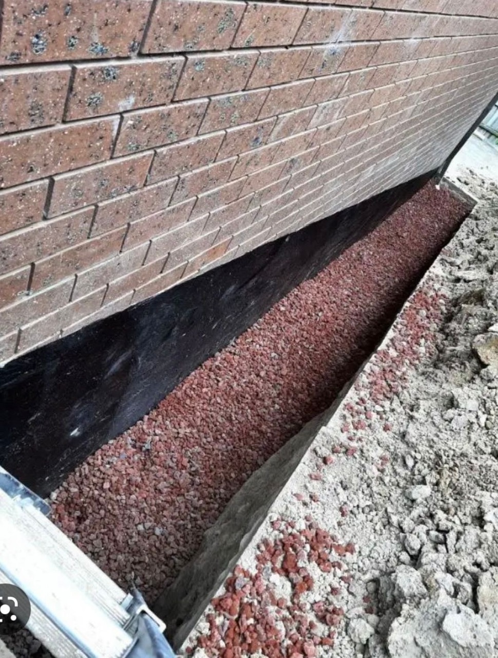 Exterior foundation waterproofing on a brick foundation in Greater Boston, with a black waterproof coating sealing the wall, by Three Hills Masonry & Foundations.