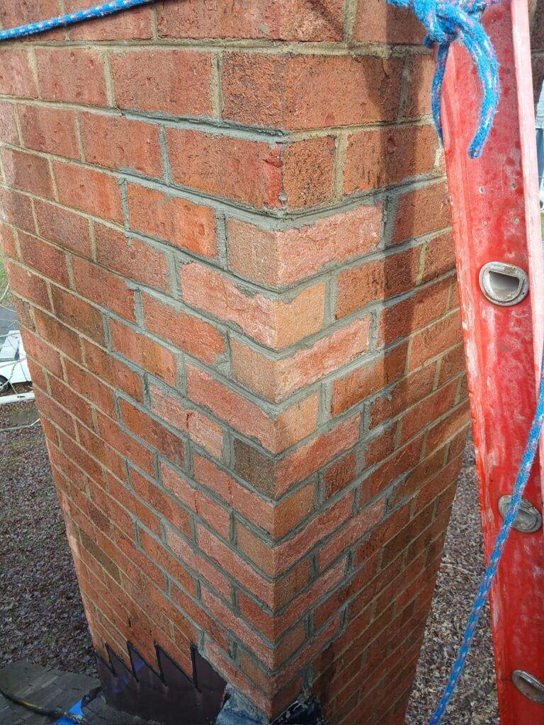 Freshly repointed brick chimney with clean, tight mortar joints after repair.