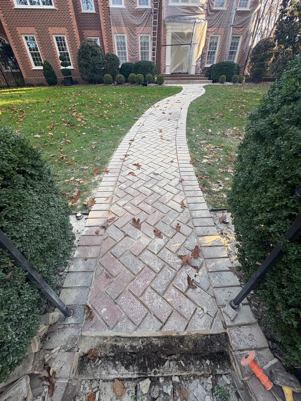 A curved brick walkway leading across a lawn to the entrance of a Greater Boston home, by Three Hills Masonry & Foundations
