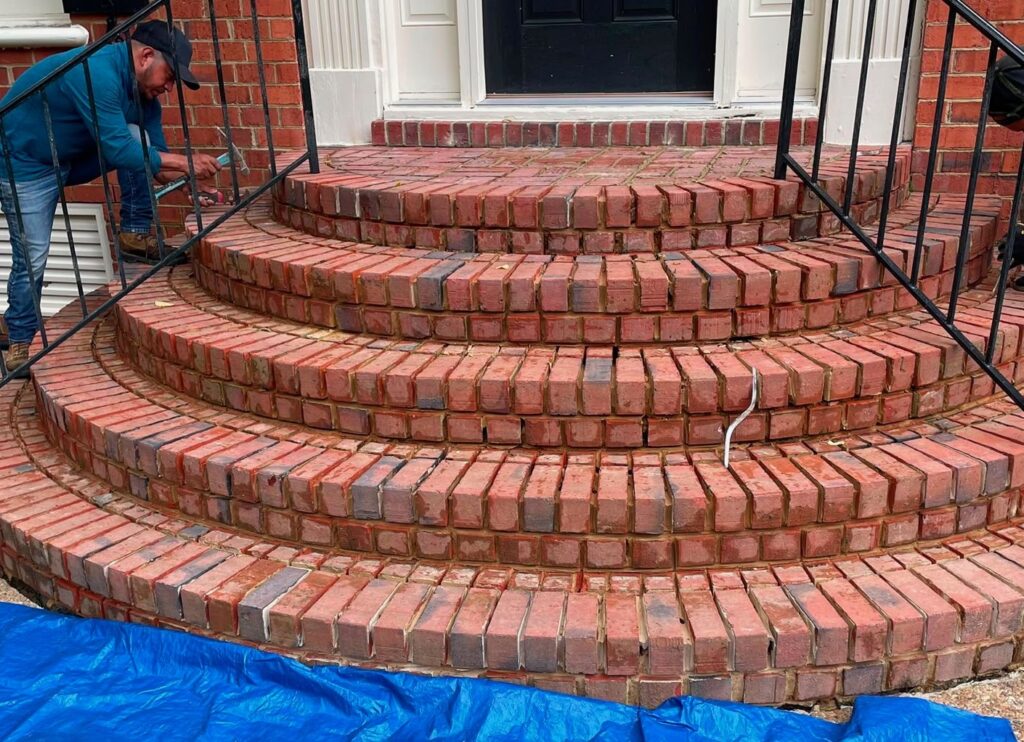 A mason repointing old brick mortar joints on steps at a Greater Boston home.