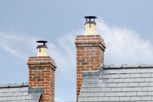 Brick chimneys with sealed crowns and metal caps rising above a slate roof.